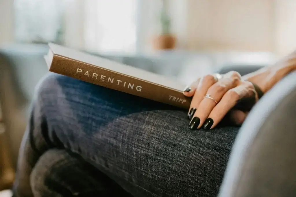 A woman holding a book called "parenting", an advantage of moving to Germany with your family is paid parental leave.