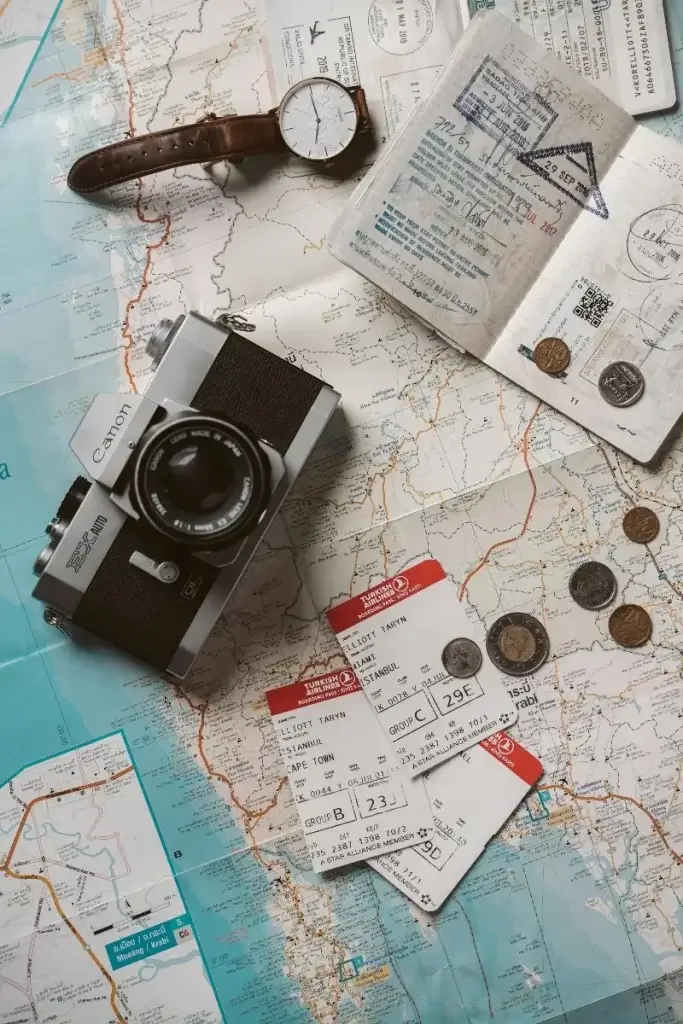 Flat lay image of world map, camera, coins and boarding passes, inspiring use of a family travel budget to get the dream vacation started.