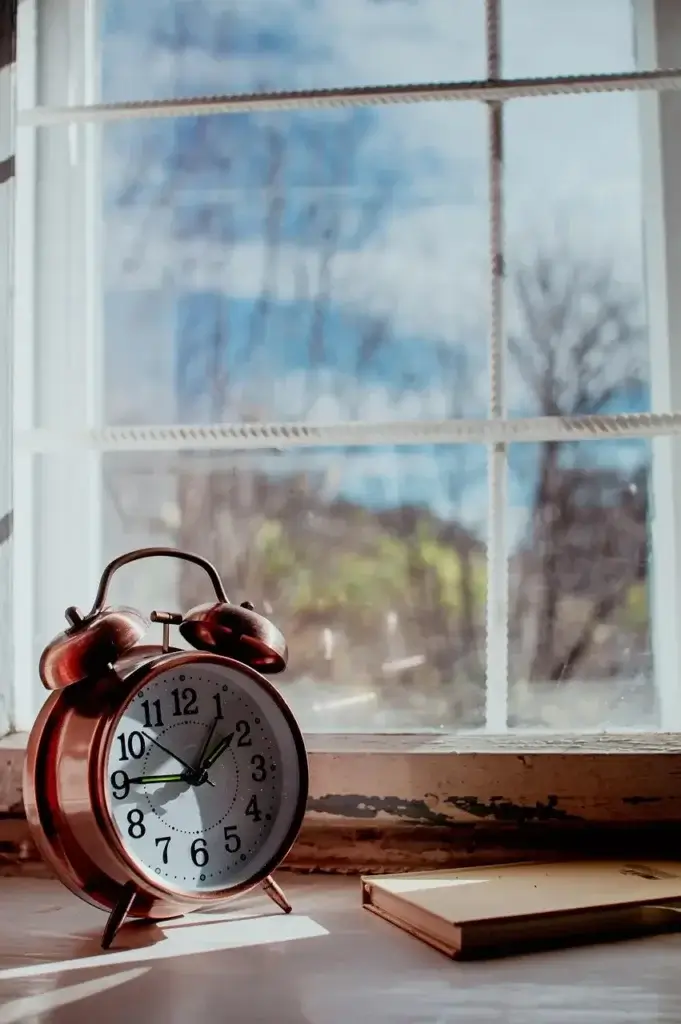 An alarm clock in front of a bright window, a strategy for beating jet lag.