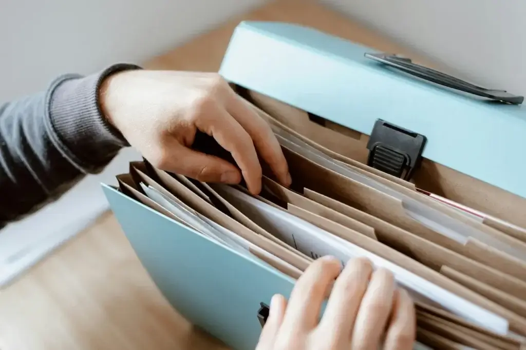 Mother's hands flipping through a document folder holding all vital documents for her family's relocation abroad.