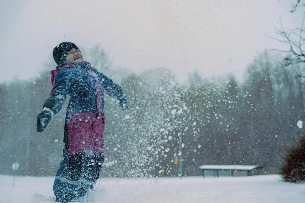 Child playing in snow after relocating abroad with her family to a new climate.